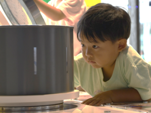 子どもが筒の中をのぞく実験装置を体験している写真